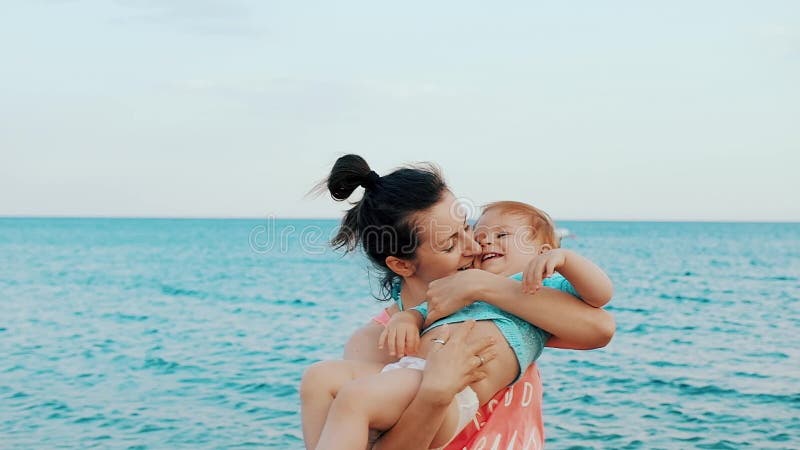 有她的小女婴的年轻母亲获得在海滩的乐趣在夏日